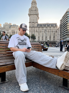 Pantalón deportivo baggy gris Vinnare, chico sentado en un banco de la Plaza Independencia, Montevideo